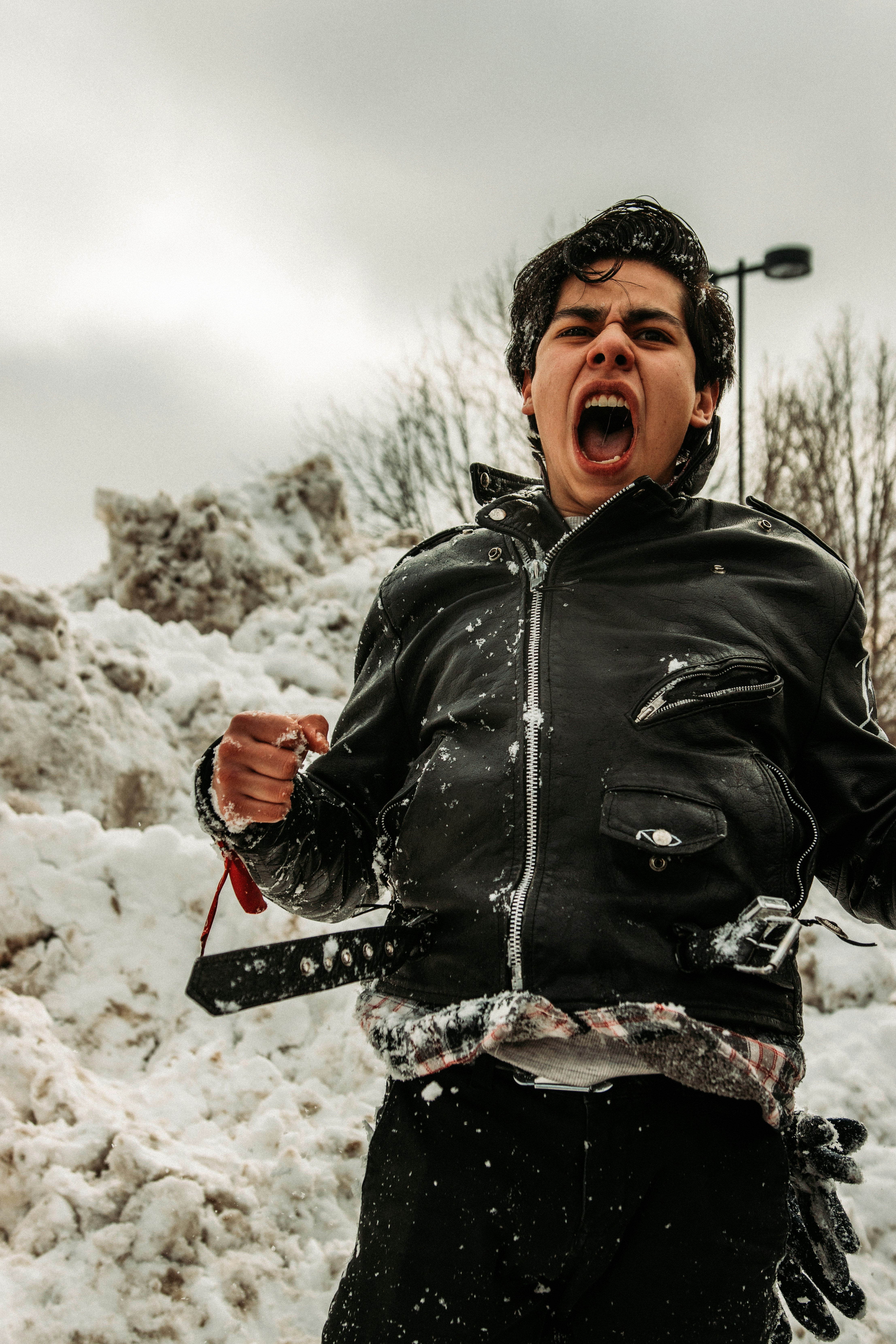 man in black leather jacket standing on snow covered ground during daytime